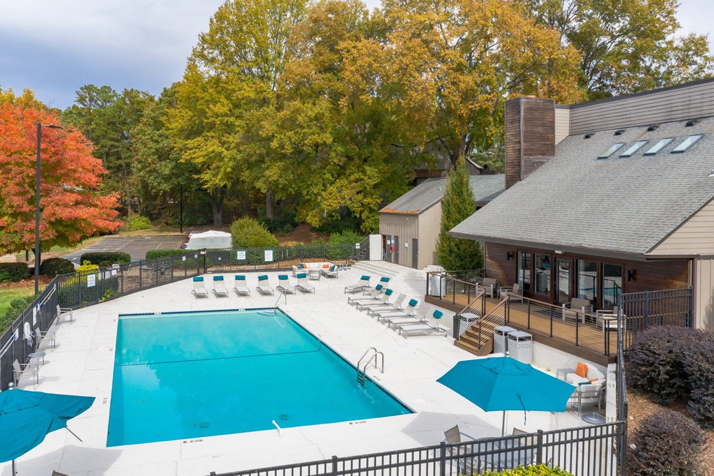 a resort style pool with lounge chairs and umbrellas in front of a house