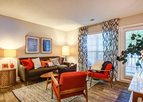 A living room with a red chair and a brown couch.