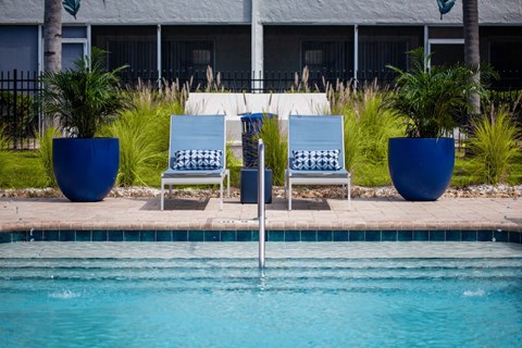 three blue and white chairs sitting next to a swimming pool