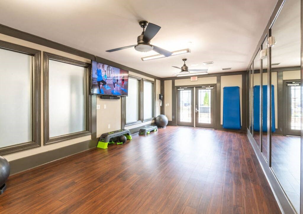 a workout room with a wood floor and a tv