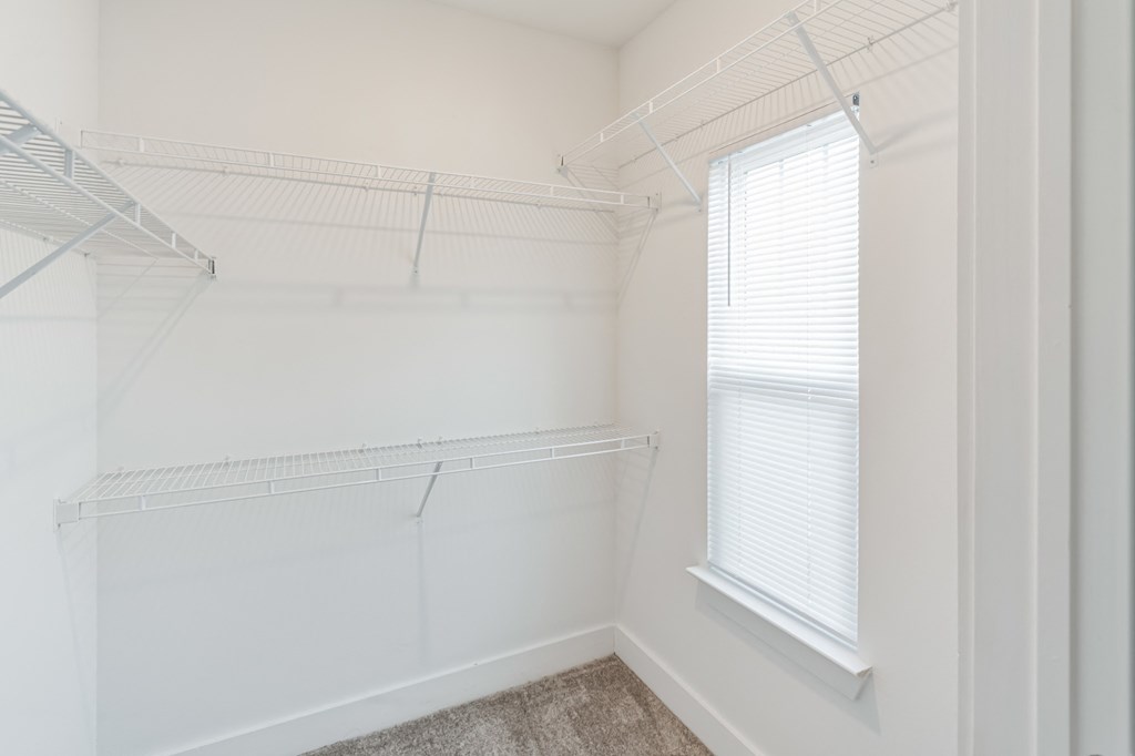 an empty closet in a home with white walls and a window