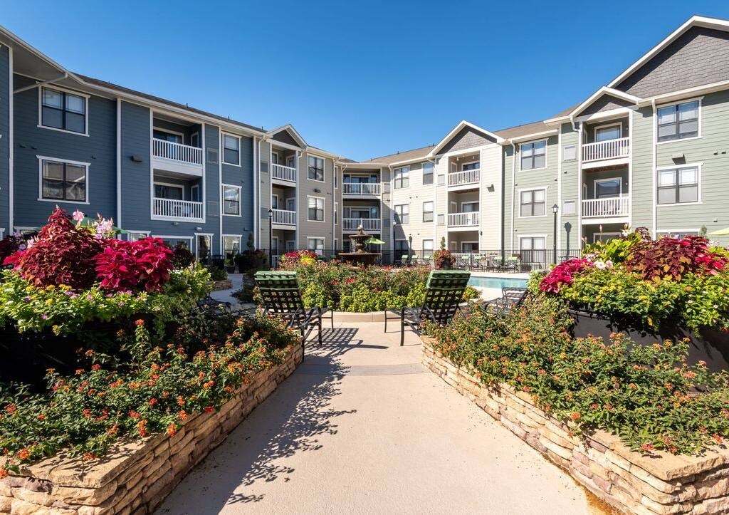 an exterior view of an apartment building with a pool and landscaping
