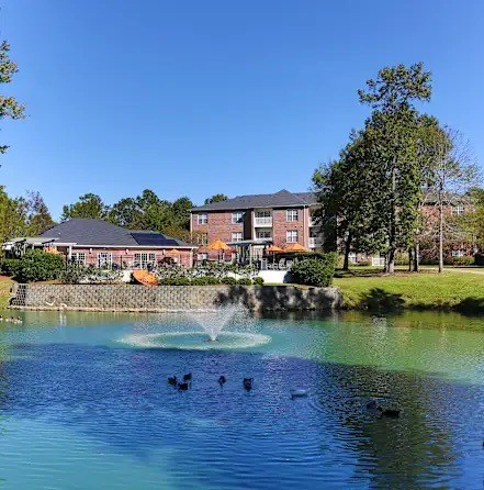 A fountain in the middle of a pond with a building in the background.