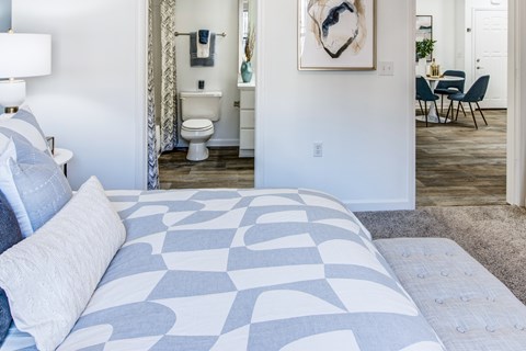 A bedroom with a large bed and a chair in the background.