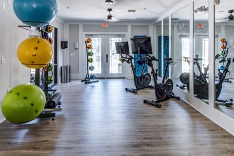A gym with exercise equipment and mirrors on the wall.