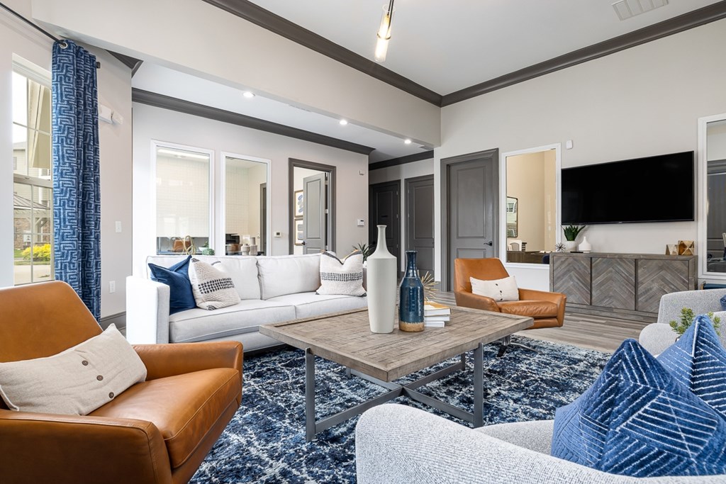 A living room with a brown leather chair and a white couch with a blue pillow.