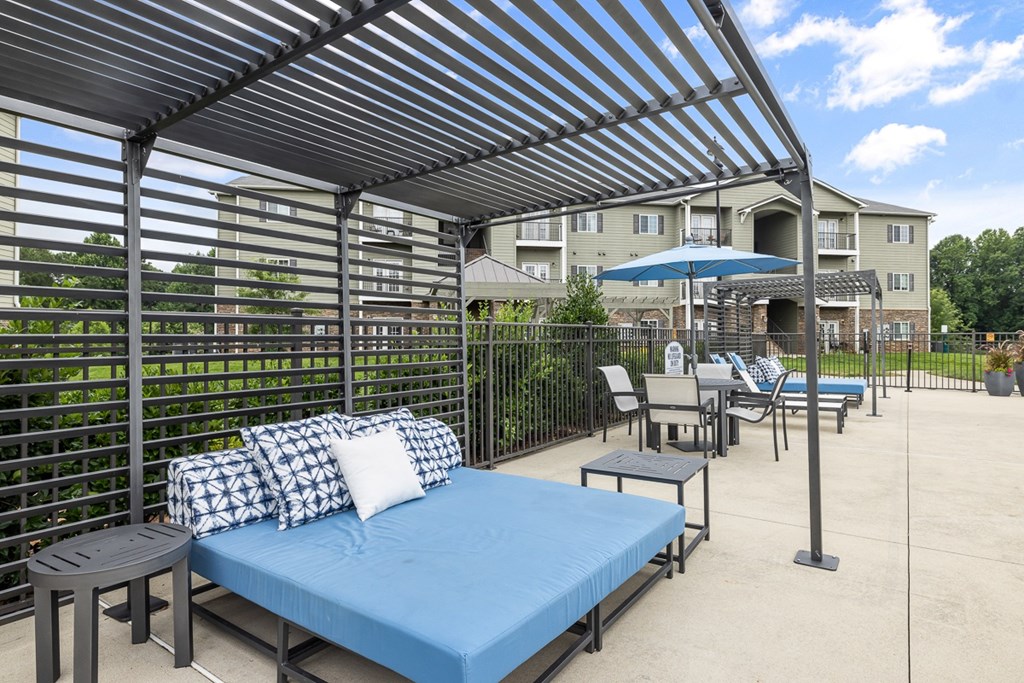 A patio with a blue mattress and a canopy.