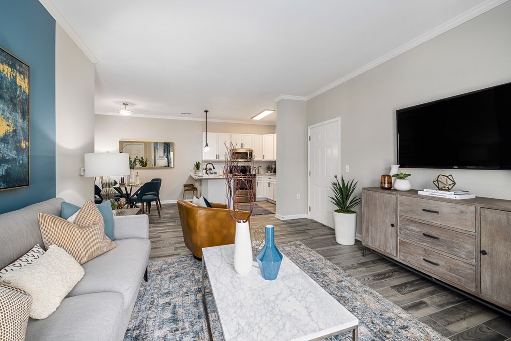 A living room with a grey couch and a blue vase on the coffee table.