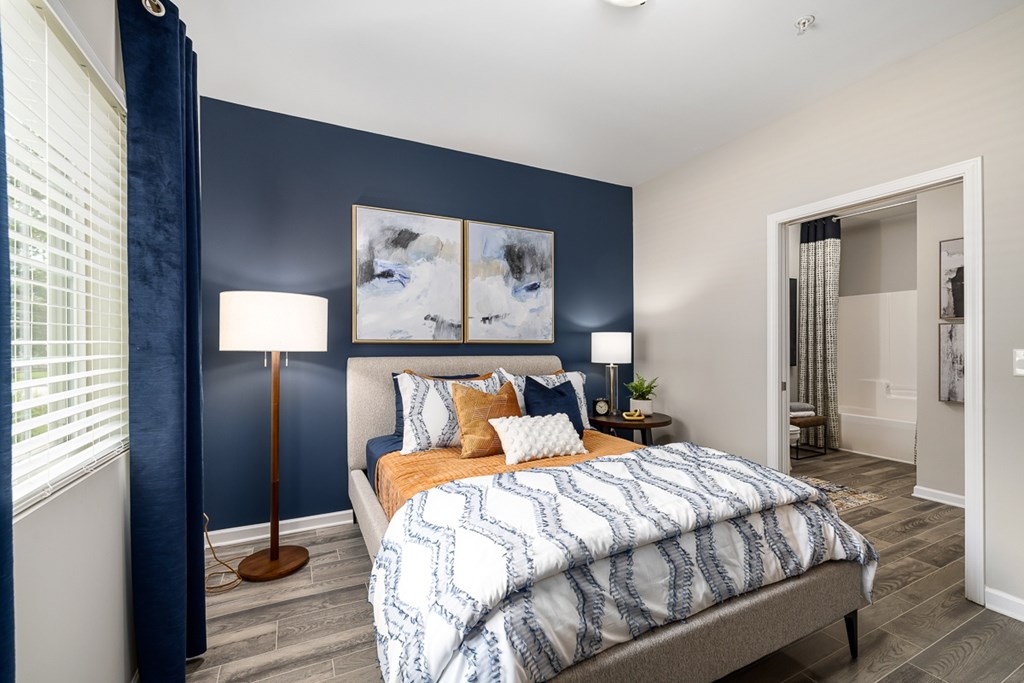 A bedroom with a bed, two lamps, and a painting on the wall.