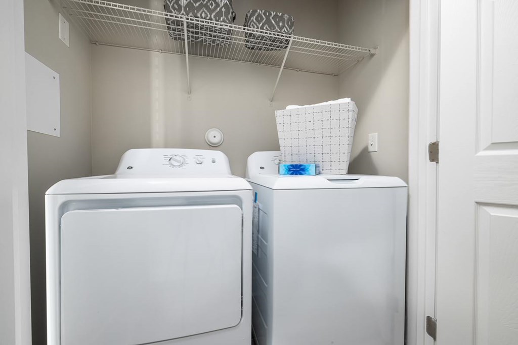 Two white washing machines in a small laundry room.