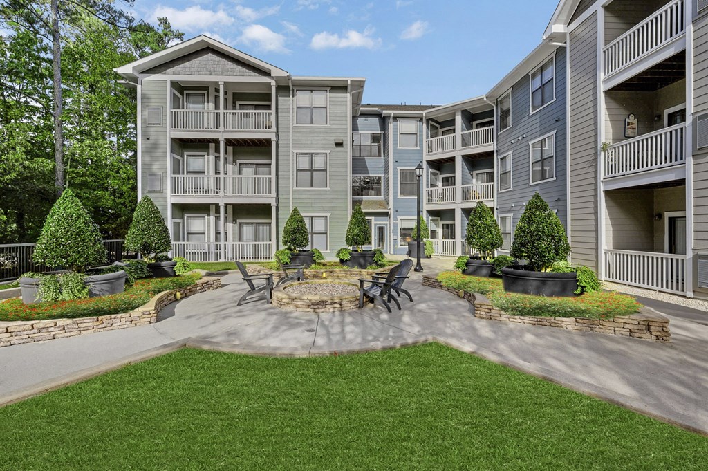 an outdoor patio with a fire pit in front of an apartment building