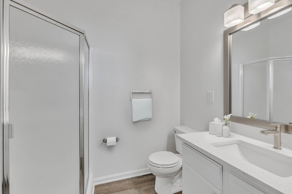 A white bathroom with a toilet, sink, and mirror.