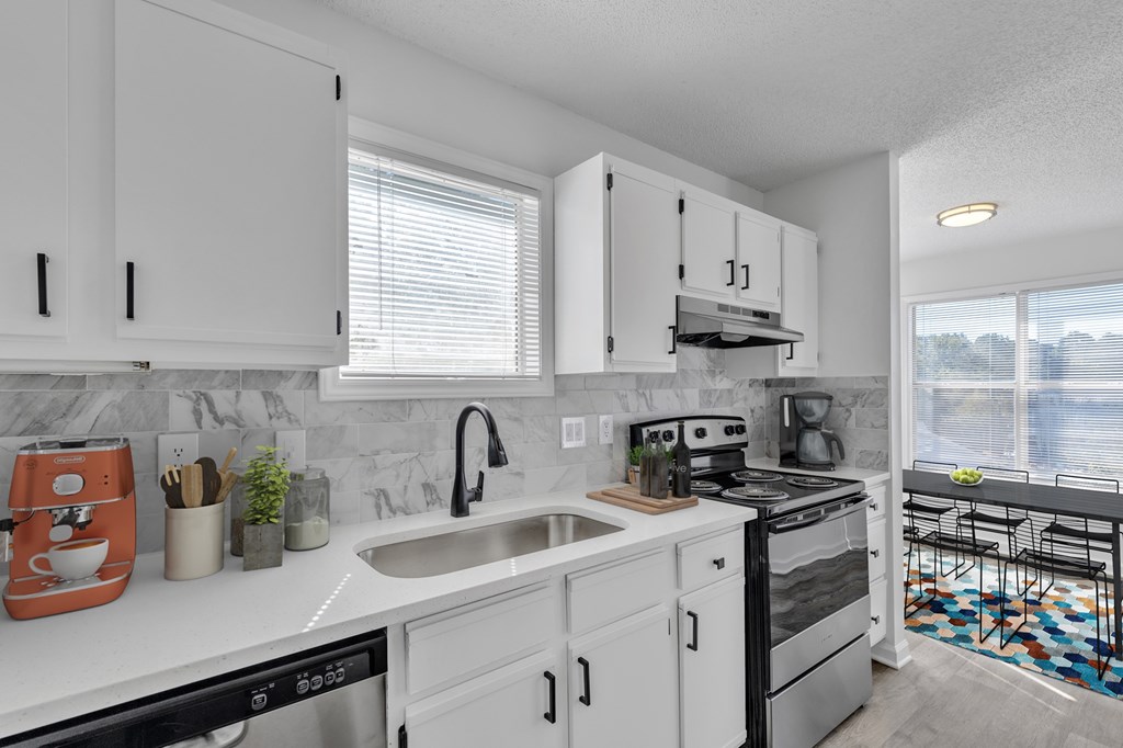 A modern kitchen with white cabinets and a black stove top oven.