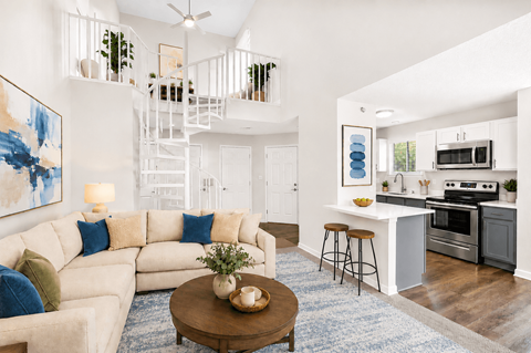 A living room with a white couch and a blue rug.