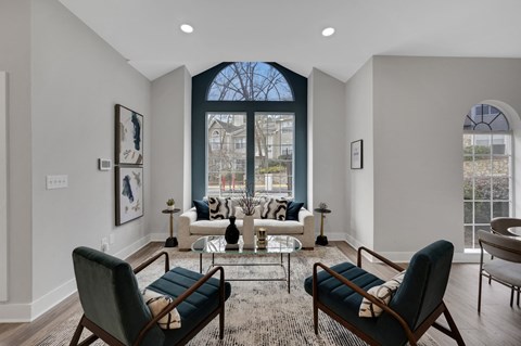 a living room with a large window and a couch and chairs