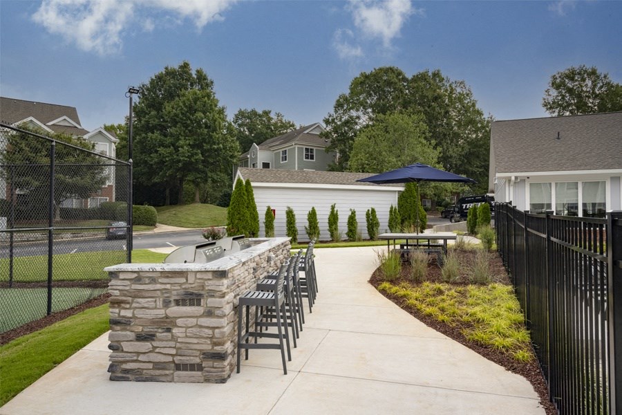 a patio with a bar and chairs and a fence