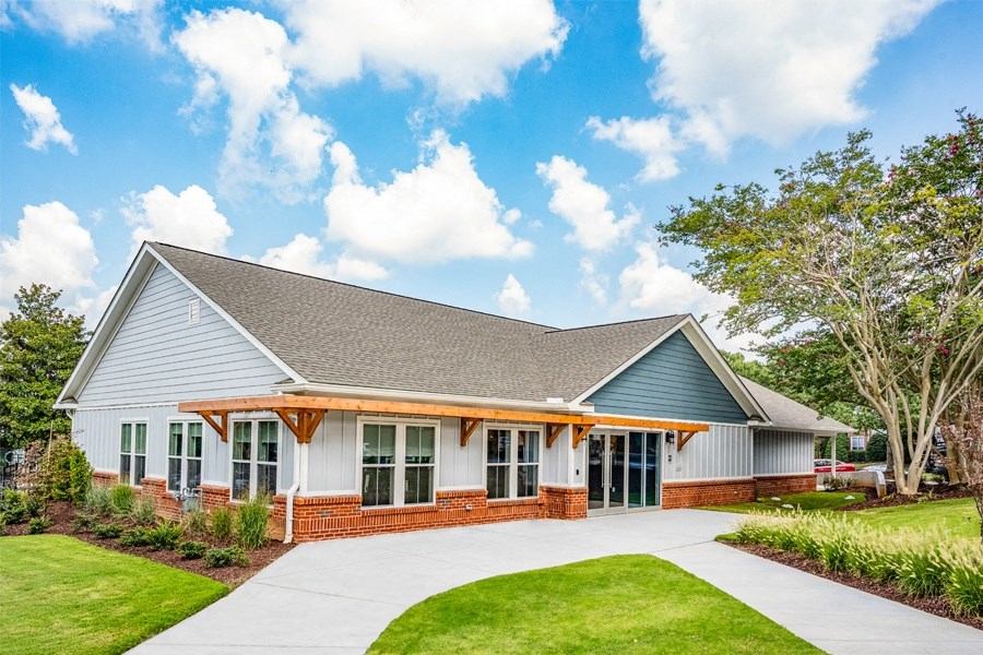 the front of a white house with a driveway and grass