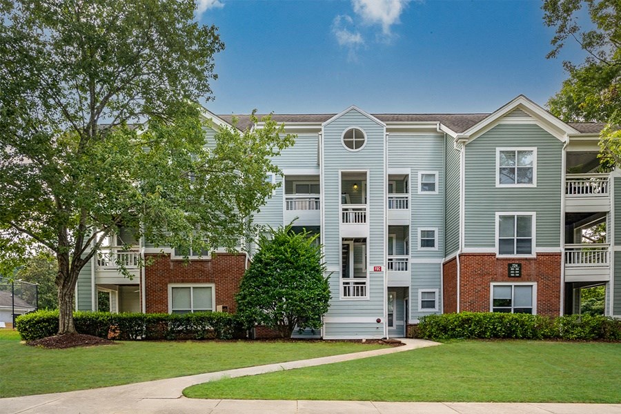 an apartment building with a green lawn and trees