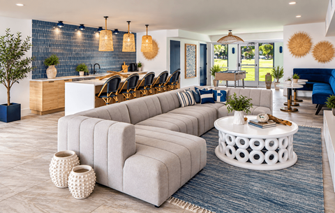 A modern living room with a large grey sofa and a white coffee table.