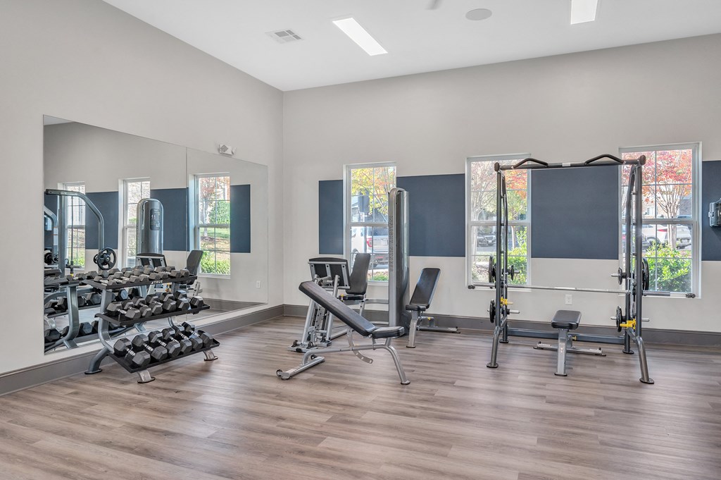 A spacious gym with a variety of equipment and mirrors on the wall.