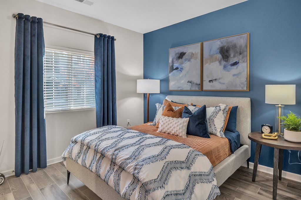 A bedroom with a bed, a nightstand, and a painting on the wall.