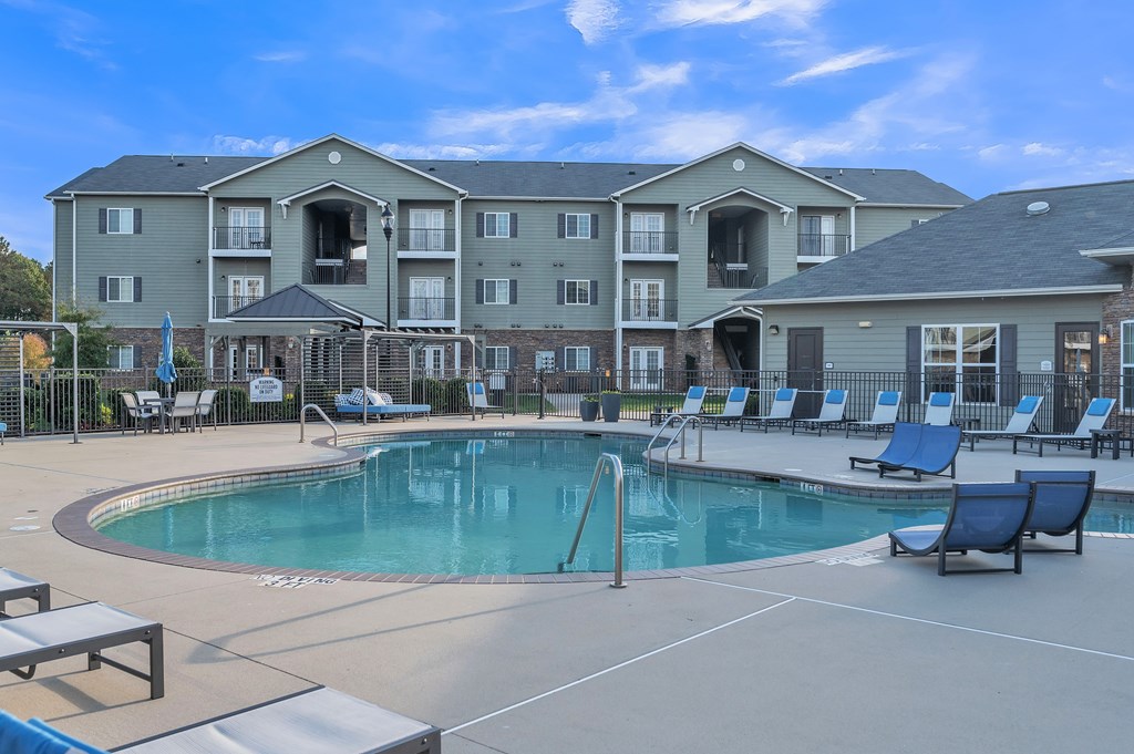 A large swimming pool in front of a multi-story apartment building.