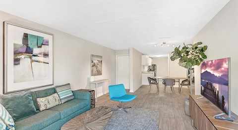 A living room with a blue couch and a painting on the wall.