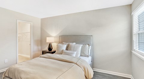 A bedroom with a large bed and a lamp on a side table.