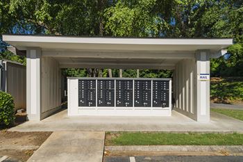 A mailbox with a white roof and black mailbox slots is situated on a sidewalk.