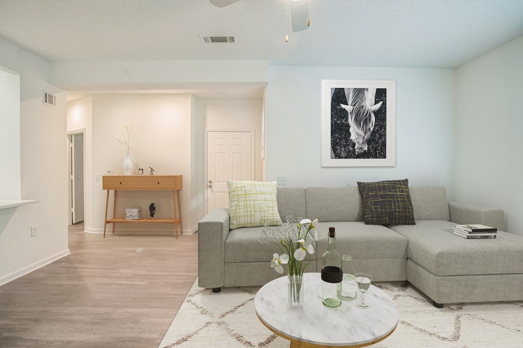 A living room with a grey couch, a coffee table, and a painting on the wall.