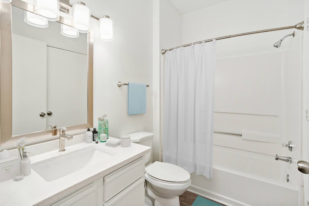 A white bathroom with a toilet, sink, and shower.