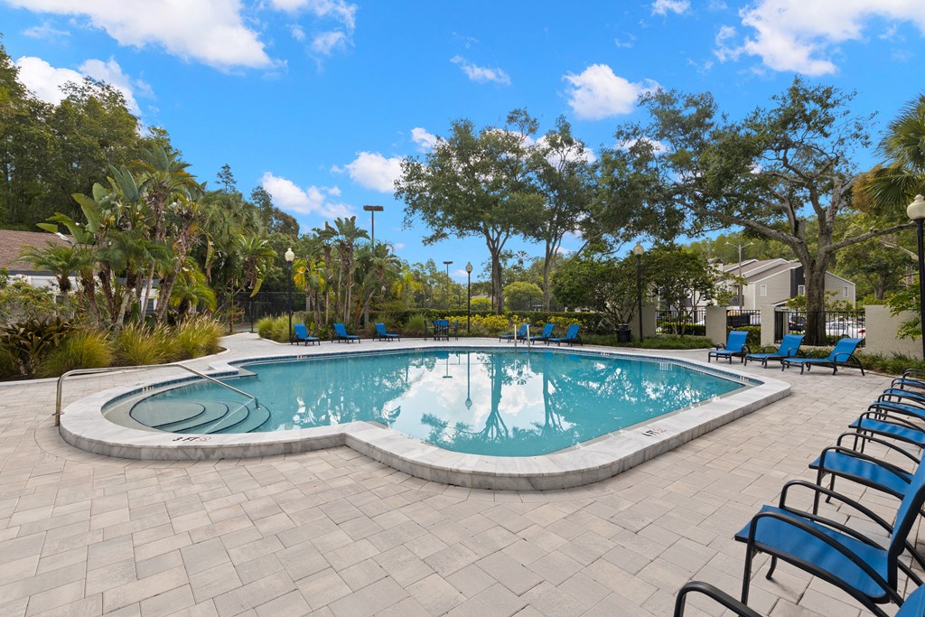 a swimming pool with blue chairs around it