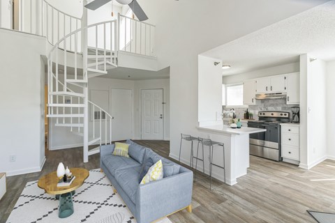 A living room with a grey couch and a spiral staircase.