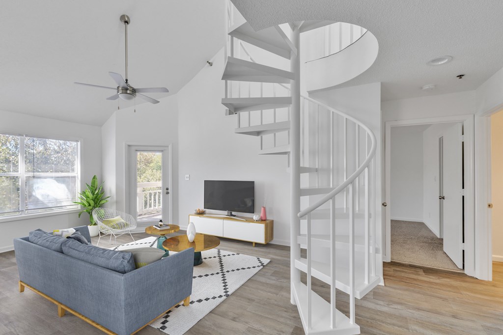 A living room with a spiral staircase and a grey couch.