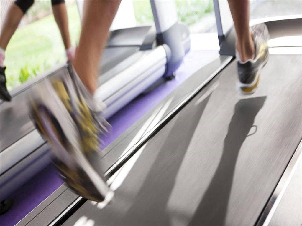 two people walking on a treadmill at a gym