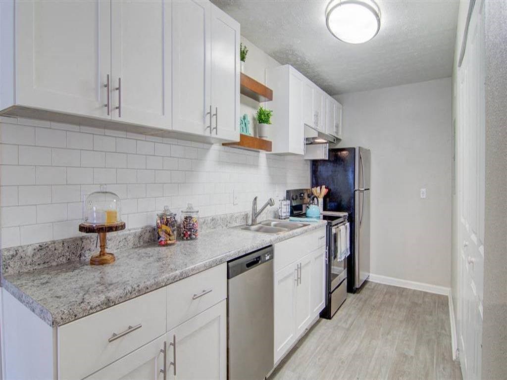 a kitchen with white cabinets and a sink and a refrigerator