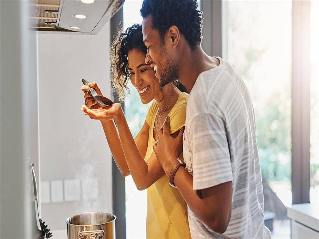 a man and woman looking at a cell phone in the kitchen