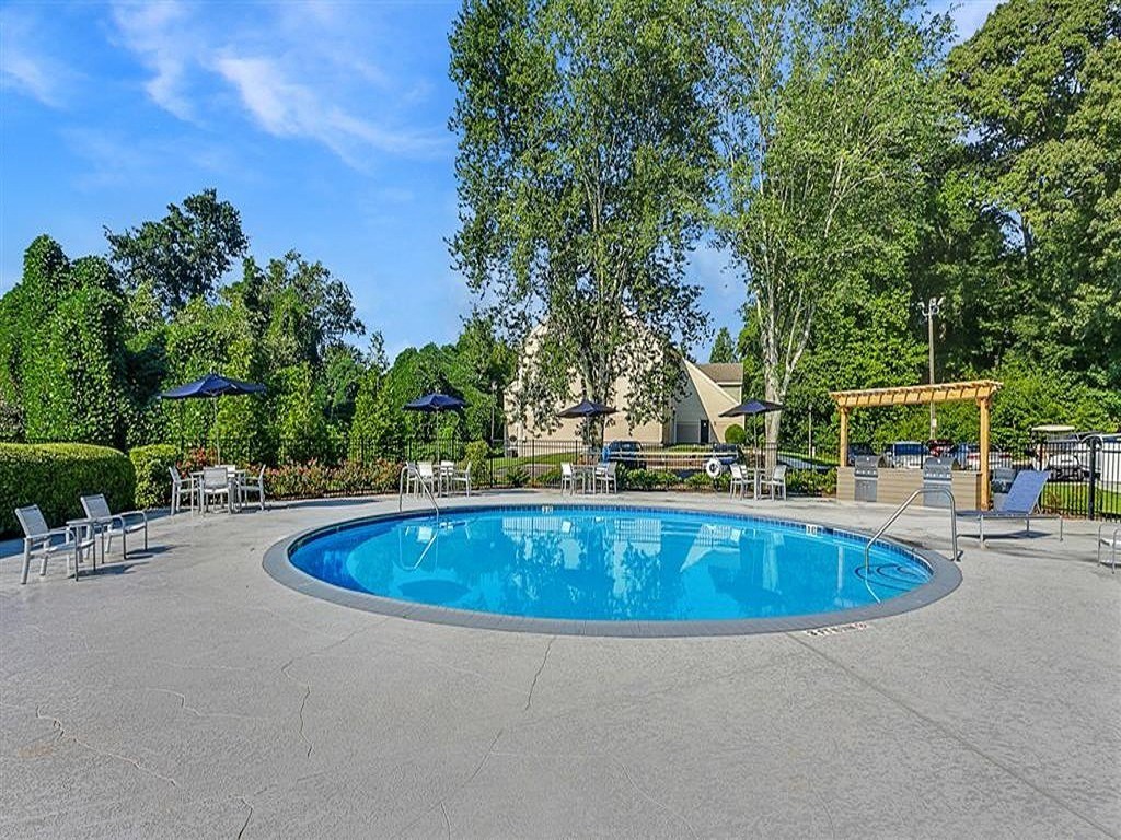 a blue swimming pool with chairs and umbrellas around it