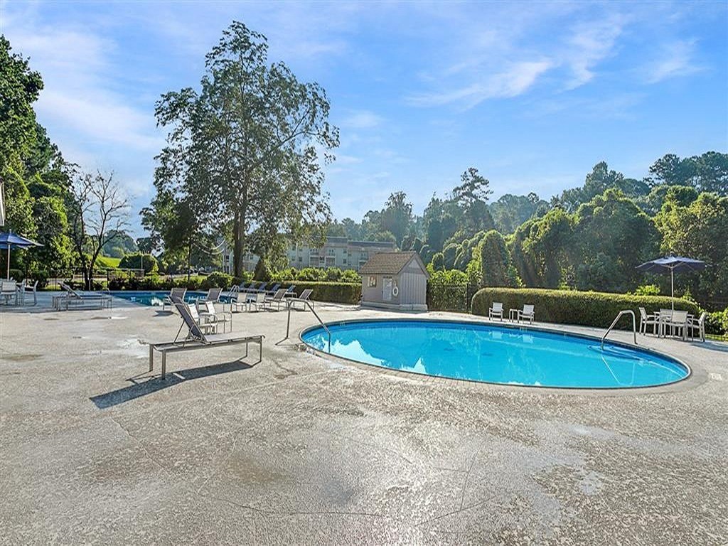 a swimming pool with chairs and umbrellas on the ground