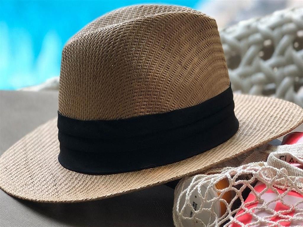 a straw hat sitting on top of a pile of clothes