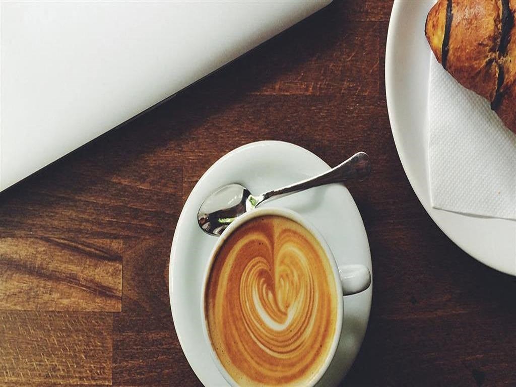 a cup of coffee on a white plate on a table