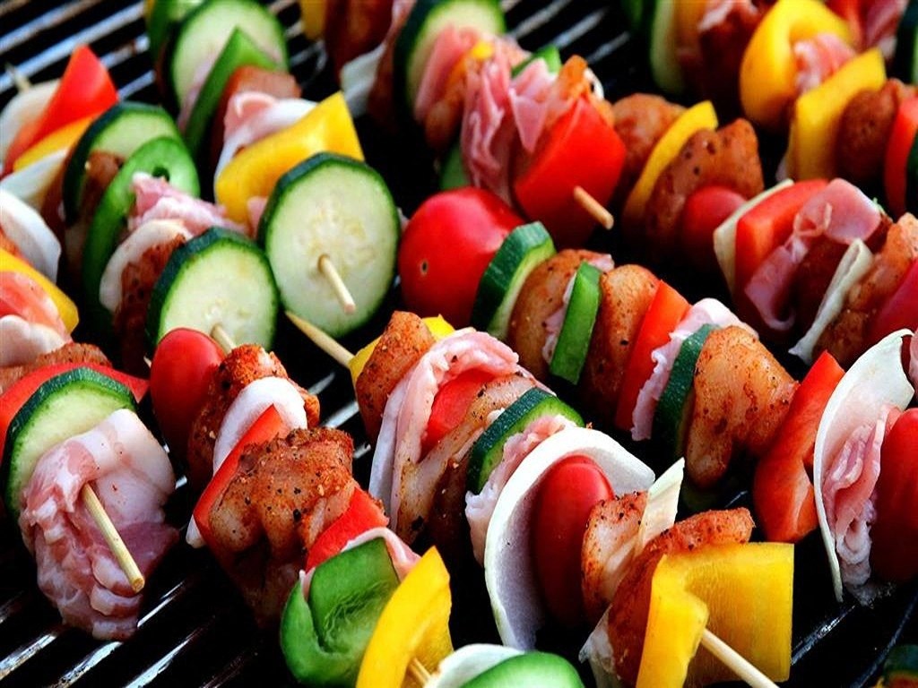 a bunch of skewers of food on a grill