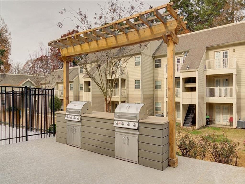 a backyard with two barbecue grills and a wooden structure
