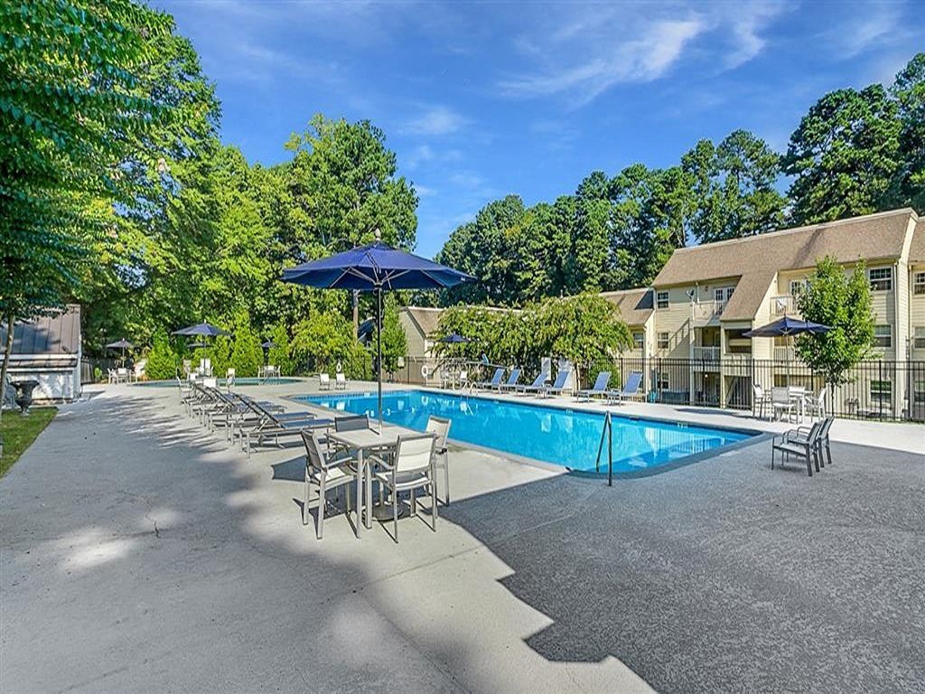 a pool with chairs and umbrellas next to a building