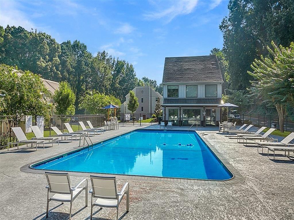 a large pool with chairs around it in front of a house