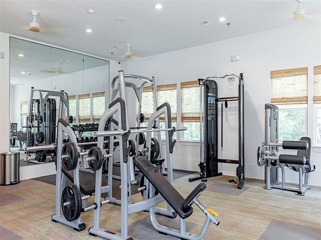 the home gym has a lot of equipment and mirrors