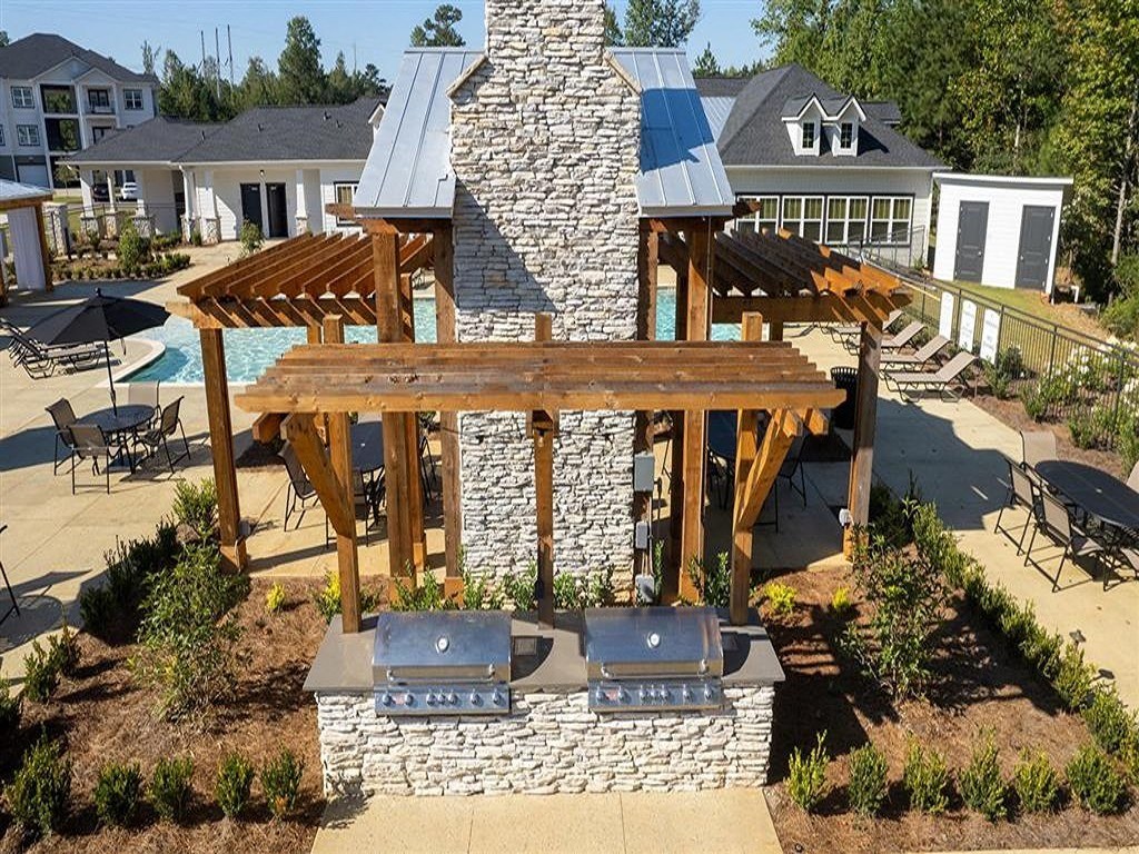 a backyard with a stone structure and a wooden pergola