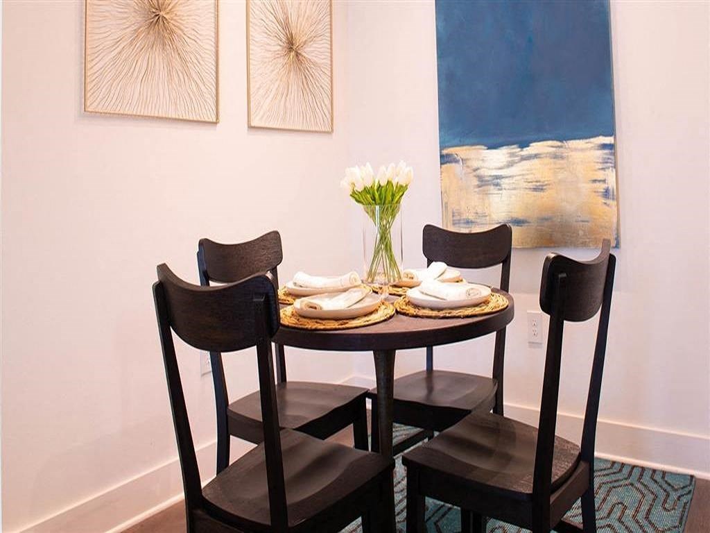 a dining room table with three chairs and a vase of flowers