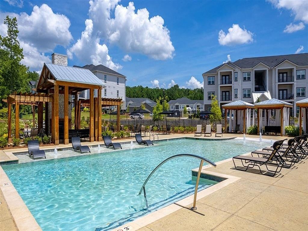 a swimming pool with lounge chairs in front of an apartment building