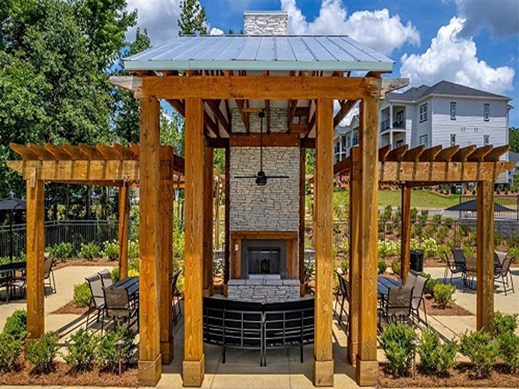 the gazebo with a stone fireplace and a patio with tables and chairs
